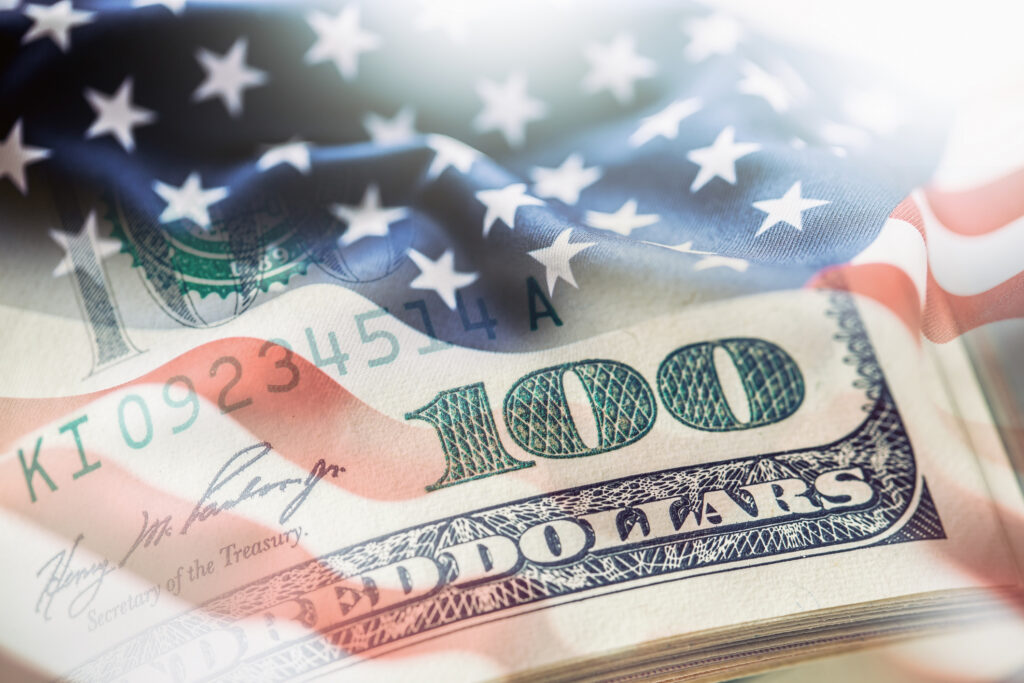 USA flag and American dollars. American flag blowing in the wind and 100 dollars banknotes in the background.