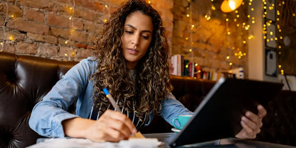 Waitress closing her shift and doing the books at a cafe using a digital tablet.