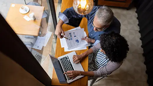 An overhead view of an advisor and entrepreneur collaborating over a laptop and documents, representing active corporate tax planning for founders.