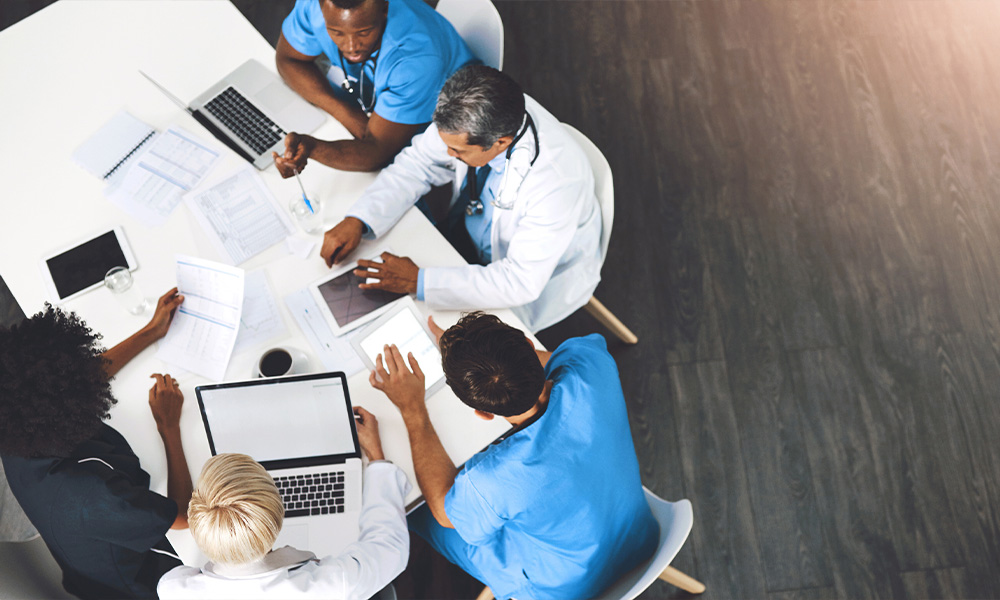 Physicians and healthcare advisors meeting around a table to discuss practice management and strategy.